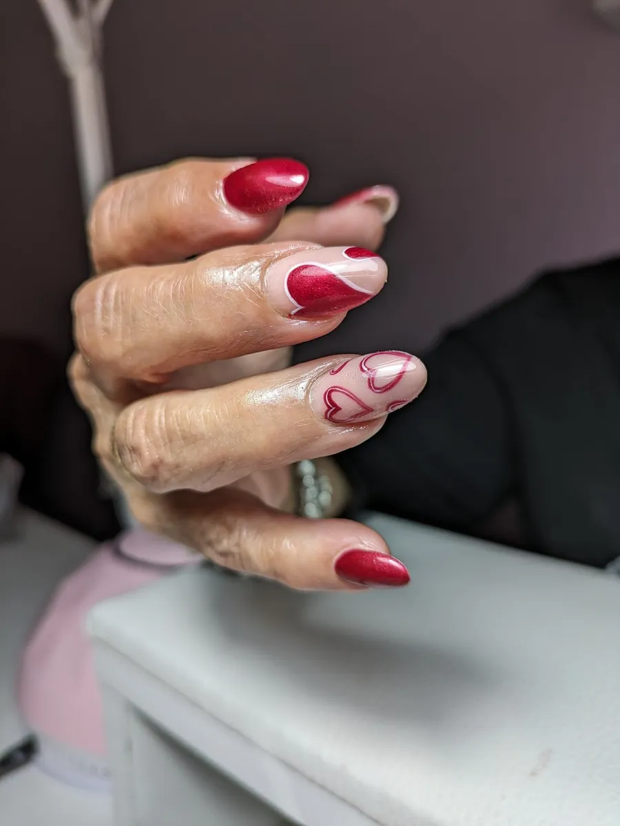Nail art con diseño floral pintado a mano en rojo y blanco